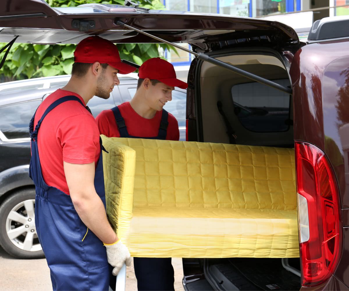 Umzugshelfer laden ein gelbes Sofa in einen Transporter – Preiswert umziehen Görlitz