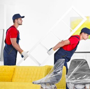 Umzug in Görlitz Zwei Helfer tragen ein Möbelstück an einem gelben Sofa vorbei – Umzug in Görlitz