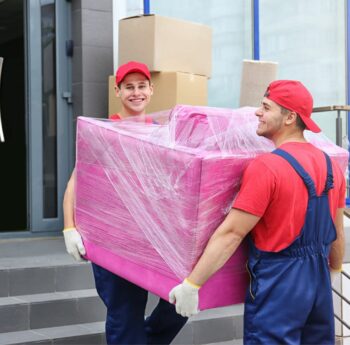 Umzug in Görlitz Zwei Umzugshelfer tragen ein in Folie gepacktes Möbelstück – Umzug in Görlitz