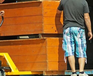 Möbelaufzug Zwei Helfer tragen einen Holzschrank aus einem Lkw – Möbelaufzug