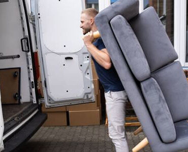 Möbellift Görlitz Möbellift Görlitz: Helfer tragen ein graues Sofa aus einem Transporter