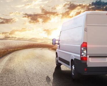 Transporter für den Umzug Weißer Transporter auf einer Straße im Abendlicht – Transporter für den Umzug